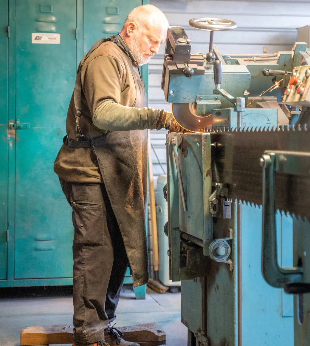 L'affûteur au travail devant sa machine d'affûtage dans l'atelier