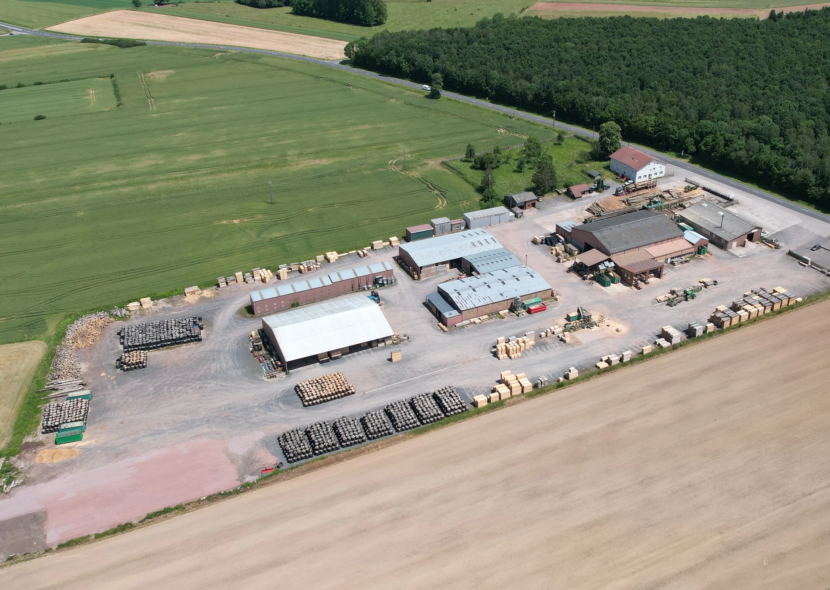 Vue aérienne de la scierie Janès Wood Industries entourée de champs et de forêts